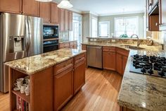 a kitchen with wooden cabinets and granite counter tops, stainless steel appliances and an island