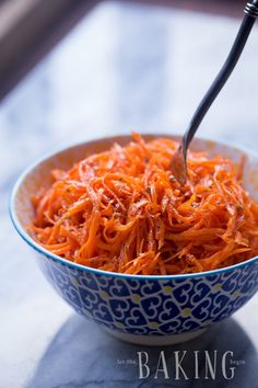 a blue and white bowl filled with shredded carrots