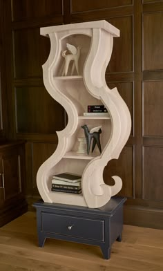 a white shelf with books and other items on it next to a wooden paneled wall