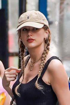 a woman with braids wearing a hat and holding a cell phone in her hand