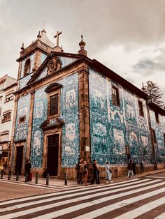 people are standing in front of an old building with blue and white tiles on it