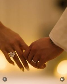 two people holding hands with rings on their fingers and one is wearing a wedding ring