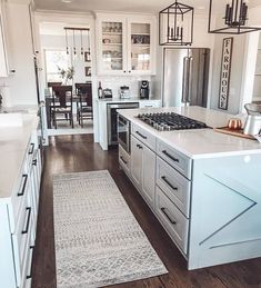 a kitchen with white cabinets and an island in the middle, along with a rug on the floor