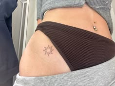 a woman's stomach with a small tattoo on her lower back and the sun behind it