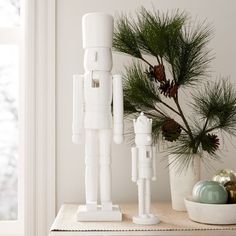 a white robot statue sitting on top of a table next to a potted plant