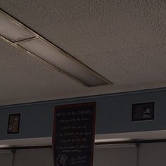 there is a sign on the wall in front of some pictures hanging from the ceiling