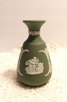 a green vase sitting on top of a white doily