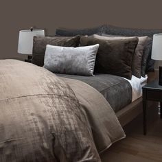 the bed is made with brown linens and pillows on top of it, along with two nightstands