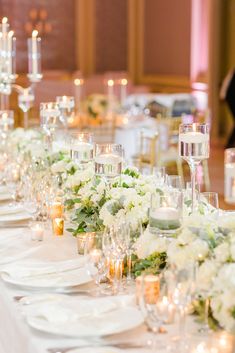 the table is set with white flowers and place settings