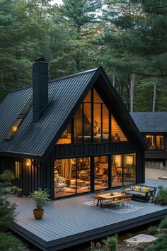 a house that is surrounded by trees and has a deck in front of the house