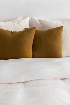 two brown and white pillows sitting on top of a bed next to eachother