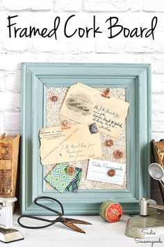 framed cork board with old papers and scissors on the table next to some other items