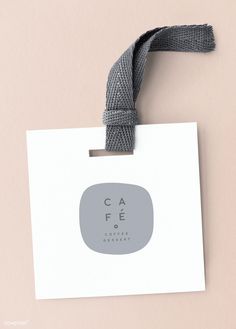 a white card with a gray ribbon hanging from it's side on a pink background