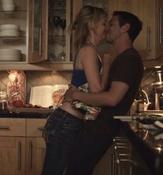 a man and woman kissing in the kitchen