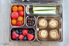 an open lunch box filled with fruit and veggies on top of a wooden table