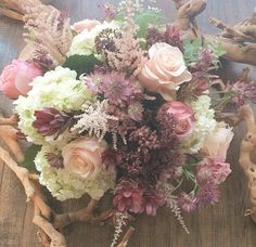 a bouquet of flowers sitting on top of a wooden table next to driftwood pieces