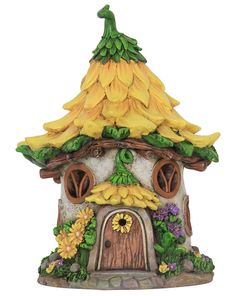 a yellow and white clock tower with bananas on it's roof, surrounded by flowers