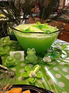 there is a green frog sitting in front of a bowl of food on the table