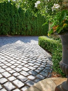 a brick paved driveway surrounded by trees and shrubbery