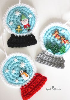 three crocheted ornaments with santa hats and snow globes in them on a white surface