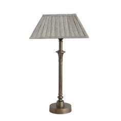 a lamp that is sitting on top of a white table cloth covered flooring with a beige fabric shade