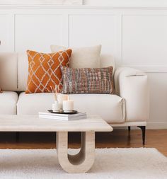 a living room with white couches and pillows on top of the sofa is filled with candles