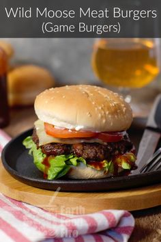 a plate with a hamburger on it next to a glass of beer