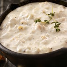 a skillet filled with white sauce and garnished with green sprigs