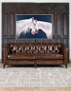 a brown leather couch sitting in front of a painting