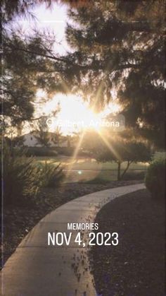 the sun is shining through some trees and bushes in front of a path that leads to a park