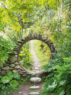 a stone arch in the middle of a lush green forest filled with flowers and plants