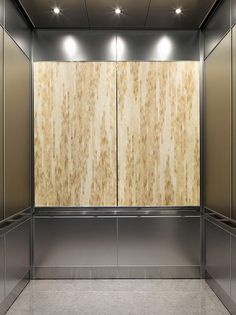 an empty elevator with wooden panels and lights on the wall above it, along with stainless steel doors