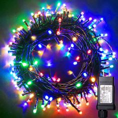 the multicolored christmas lights are arranged in a circle on a black background with an electronic charger next to it