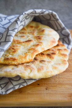 two pita breads sitting on top of a wooden cutting board