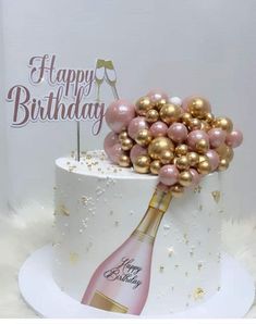 a birthday cake decorated with pink and gold balloons, champagne bottle and happy birthday sign