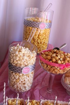 there are many different types of popcorn on the table and in glass containers with spoons