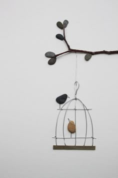 a bird in a cage hanging from a tree branch with two birds perched on it