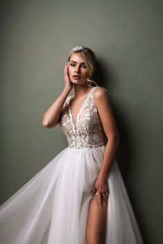 a woman in a white dress leaning against a wall with her leg on the floor