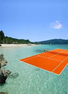 an orange tennis court floating in the ocean with rocks and water around it, surrounded by trees