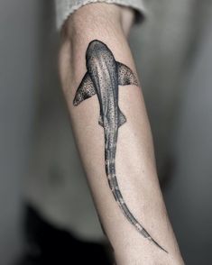 a man's arm with a black and white shark tattoo on the left forearm