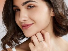 a close up of a person wearing a ring on her finger and smiling at the camera