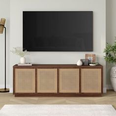 a living room with a large television mounted on the wall and wicker furniture in front of it