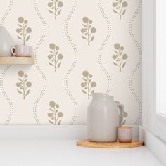 a white vase sitting on top of a counter next to a wallpapered wall