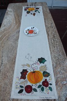 a table runner with fruit and leaves painted on it, sitting on a granite slab