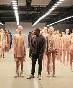 a man standing in front of a group of mannequins on the runway