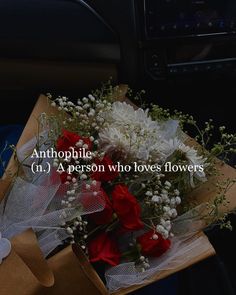 a bouquet of flowers sitting on top of a cardboard box next to a car steering wheel