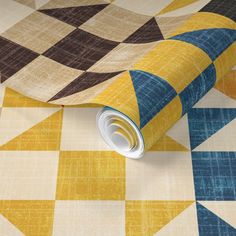 a yellow and blue checkered wallpaper with a roll of tape on the floor