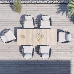 an overhead view of a table and chairs on a patio with white cushions, surrounded by palm trees