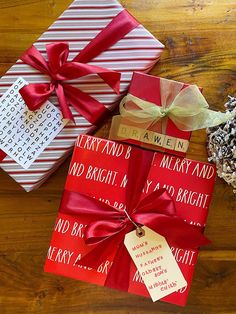 presents wrapped in red and white paper on a wooden table with tags attached to them