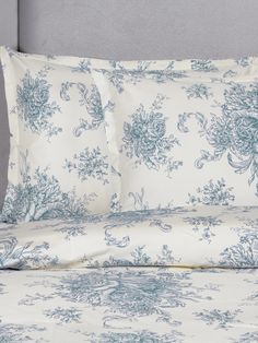 a bed with blue and white floral designs on the comforter, pillows and pillow cases